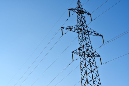 High-voltage power lines against a blue sky background. Towers for the transmission of electricity....