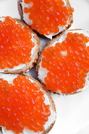 Red salmon caviar on bread and butter. A sandwich with caviar and butter on a plate.の写真素材