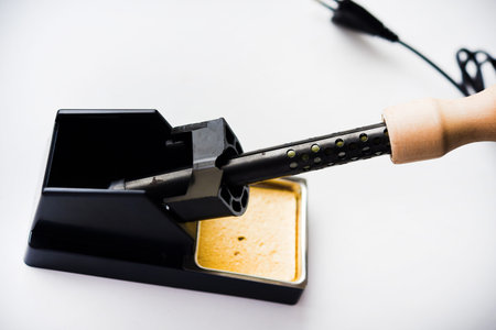 Soldering iron with a wooden handle in the holder. A soldering iron stand.