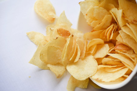 Delicious salted potato chips in a cardboard jar on a white background. Fast food.