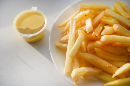 French fries on a white plate with sauce. Delicious fried crispy potatoes.の写真素材