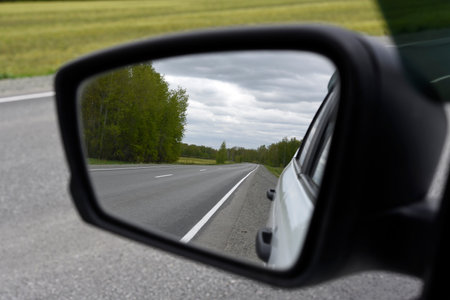 A running road in the rearview mirror of a car. An asphalt road in the forest.の写真素材