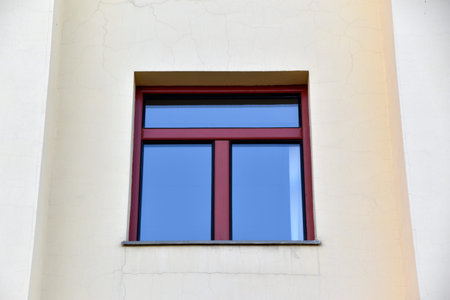 A red window on a yellow wall. A beautiful window in a classic building.
