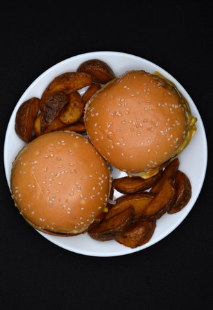 Hamburgers and homemade potatoes on a white plate. Delicious breakfast. Fast food.の写真素材