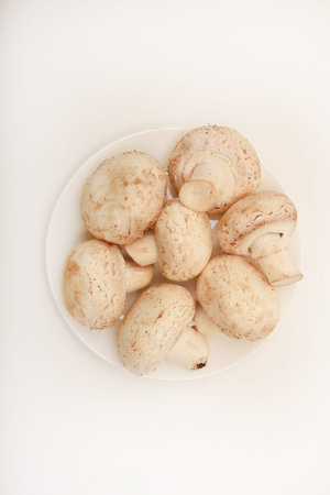Fresh champignons on a white plate. Mushrooms on a white background.の写真素材