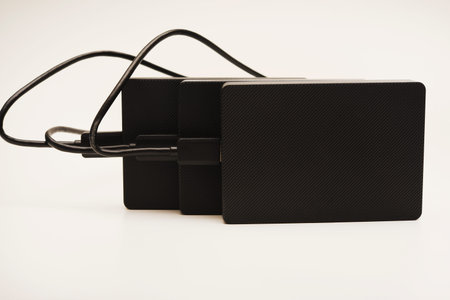 Hard drives on a white background. Modern data storage devices with USB wires.