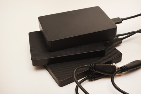 Hard drives on a white background. Modern data storage devices with USB wires.