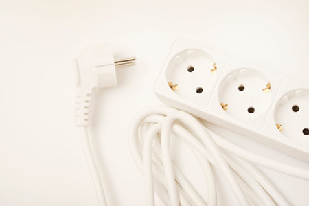 An extension cord with three sockets. White wire with sockets on a white background.
