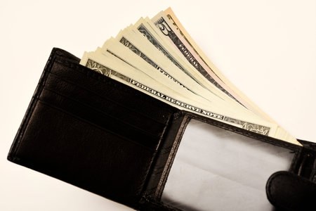 A black wallet with dollars on a white background. A wallet with money.