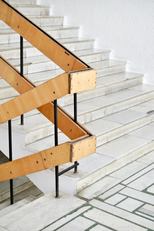 A flight of stairs with marble steps. Whitewashed walls and wooden staircase railings. The staircase of an old building.の写真素材