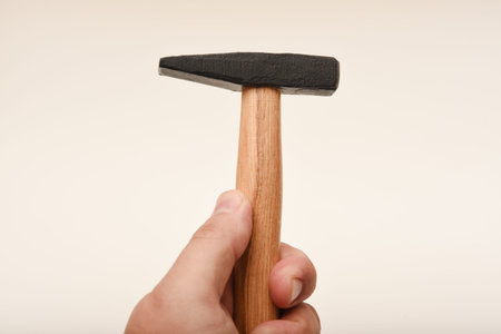 A small hammer with a wooden handle. A hammer on a white background in his hand.