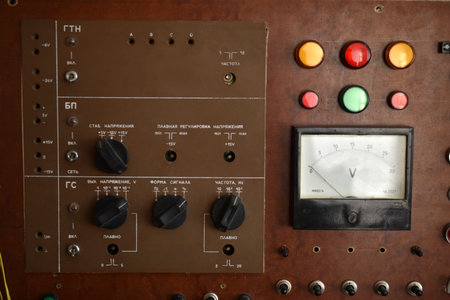 An old control board with a voltmeter, switches and lamps. Electronic control panel with buttons and...