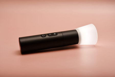 A flashlight for studio lighting. Compact flashlight for the photographer. A flashlight on a pink...