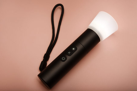 A flashlight for studio lighting. Compact flashlight for the photographer. A flashlight on a pink...