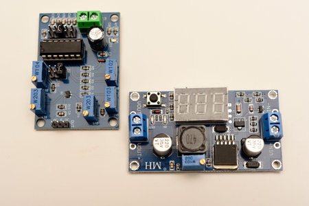 Two electronic devices on a blue printed circuit board. A small electronic device.