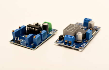Two electronic devices on a blue printed circuit board. A small electronic device.