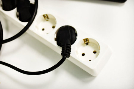 An electrical extension cord with sockets. An electrical outlet in the house.