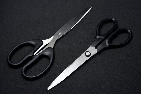 Two scissors on a black background. Stationery scissors.