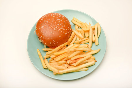 Hamburger with meat and vegetables and French fries on a plate.の写真素材