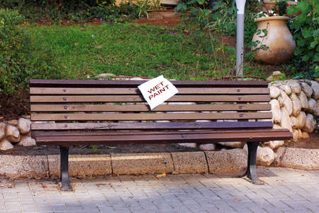 A wet paint sign on a freshly painted wooden benchの写真素材