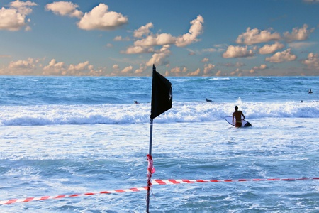 Black flag and striped red and white ribbon on the beach - swimming in the sea is prohibitedの写真素材