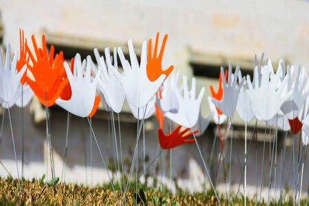 Many waving abstract hands signs or flags installed on a grassy lawn using the metal wireの写真素材