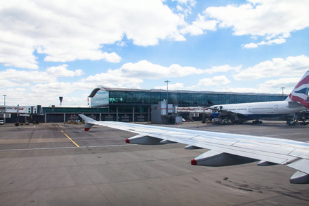 Taxiing aircraft Airbus A-320  after landing  in Heathrow Airport near British Airway passenger jet airplane  Boeing 747-400 on cloudy sky background. London. UKのeditorial素材