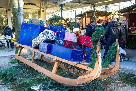Unidentified    people near old  wooden sleigh with gift boxes at Christmas market in  small german town. Baden-Baden, Germanyのeditorial素材