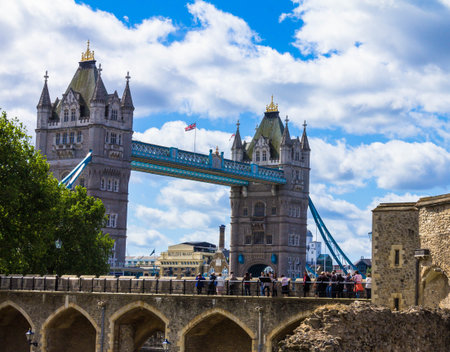 Unidentified tourists on Tower Bridge and blue sky background. London