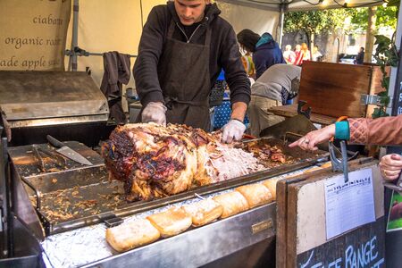 LONDON, UK - JUNE 6, 2015:  Unidentified chef cuting roasted pig  on small market at  the south bank of the River Thamesのeditorial素材