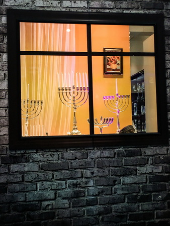 TEL AVIV, ISRAEL - DECEMBER 22, 2016: Showcase of Judaic store before the Hanukkah holiday with exposed different sizes and designs menorahs (traditional candelabra)のeditorial素材