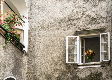Open window with flowers bouquet at building patio in old Salzburg distrist. Ausria