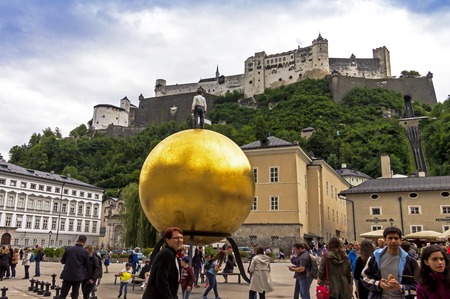 SALZBURG, AUSTRIA - July 15, 2017: Stephan Balkenhol - Sphaera, a sculpture of a man on a golden sphere on Kapitelplatz(Chaptr square)のeditorial素材