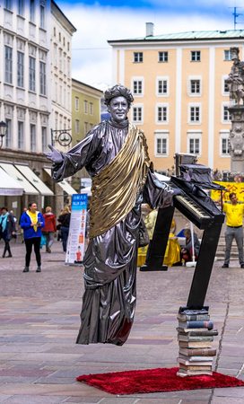 SALZBURG, AUSTRIA - JULY 15, 2017: Street artist-illusionist performing levitation trick in the old center of Salzburg, Austriaのeditorial素材
