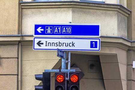 A traffic light with arrows and an exit sign for 1 and 10 highways in the direction of Innsbruck. Salzburg. Austriaのeditorial素材