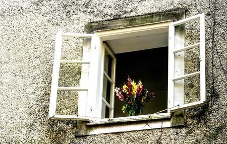 Open window with flowers bouquet at building patio in old Salzburg distrist. Ausria