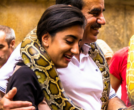 Prague, Czech Republic -July 23,2017: Young woman making photo with a huge yellow boa snake...