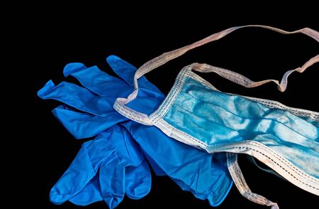 White antivirus mask and blue latex gloves on dark background. Selective focus.の写真素材