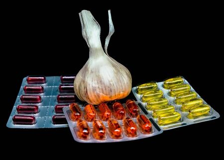 Fresh garlic , pills and vitamins in blister packs on black background with copy space. Medical pharmacy concept. Selective focusの写真素材