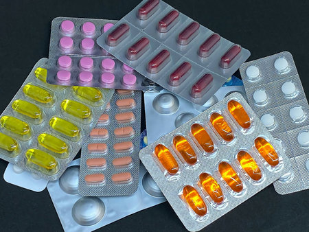 Pile of pills and vitamins in blister packs on dark background with copy space. Medical pharmacy...