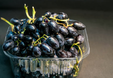 Seedless dark blue grapes in plastic package; grapes are a type of fruit growing in clusters and can...