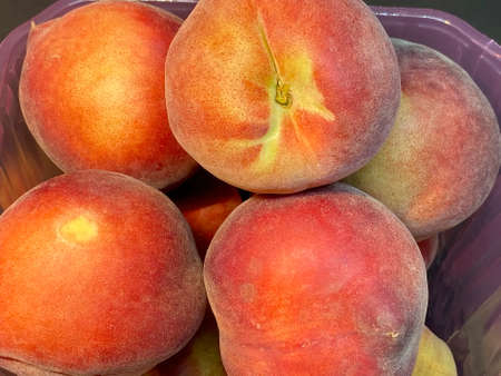 Fresh red peaches in plastic box, isolated on dark backgroundの写真素材