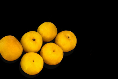 Large yellow plums on black background