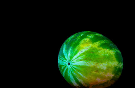 Ripe single full watermelon berry on black backgroundの写真素材