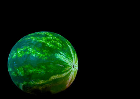 Ripe single full watermelon berry on black backgroundの写真素材