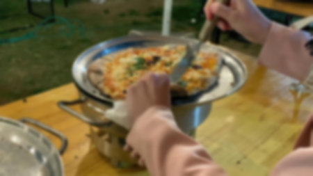 Woman taking a slice of pizza on a porcelain plate with a metal spatula. Blurred viewの写真素材