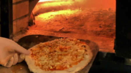 Pizza cooking in a gas brick portable oven. Blurred viewの写真素材