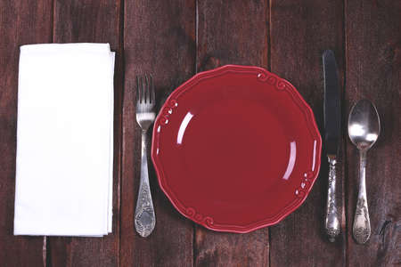 Crimson empty plate with cutlery. Table setting. Fork, knife and spoon on the table. Space for text.の写真素材