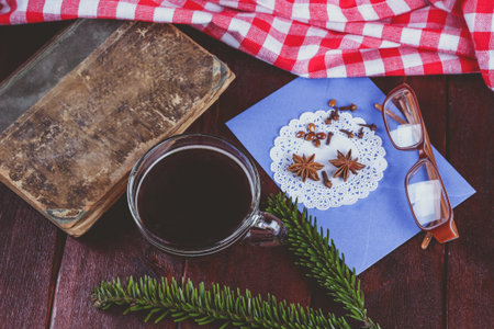 Old book, glasses, branch of pine needles, cup of coffee and an envelope on the table. Vintage still life. Reading books, relaxing with a cup of coffee.の写真素材