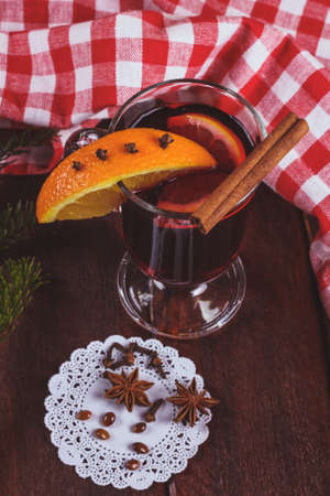 Glass of mulled wine on the table. Mulled wine with citrus slices on a table next to a Christmas tree branch and tablecloths.の写真素材
